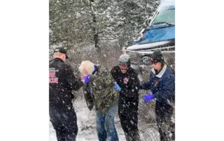 MVA - SPOFR Team Members assisting the driver up a snowy bank to a waiting ambulance.