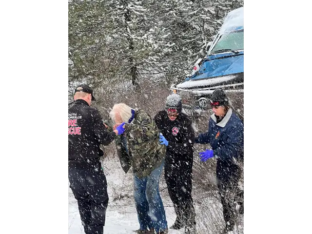 MVA - SPOFR Team Members assisting the driver up a snowy bank to a waiting ambulance.